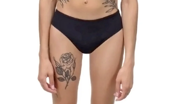 A slender person with fair skin wears a black speedo/bikini-shaped undergarment